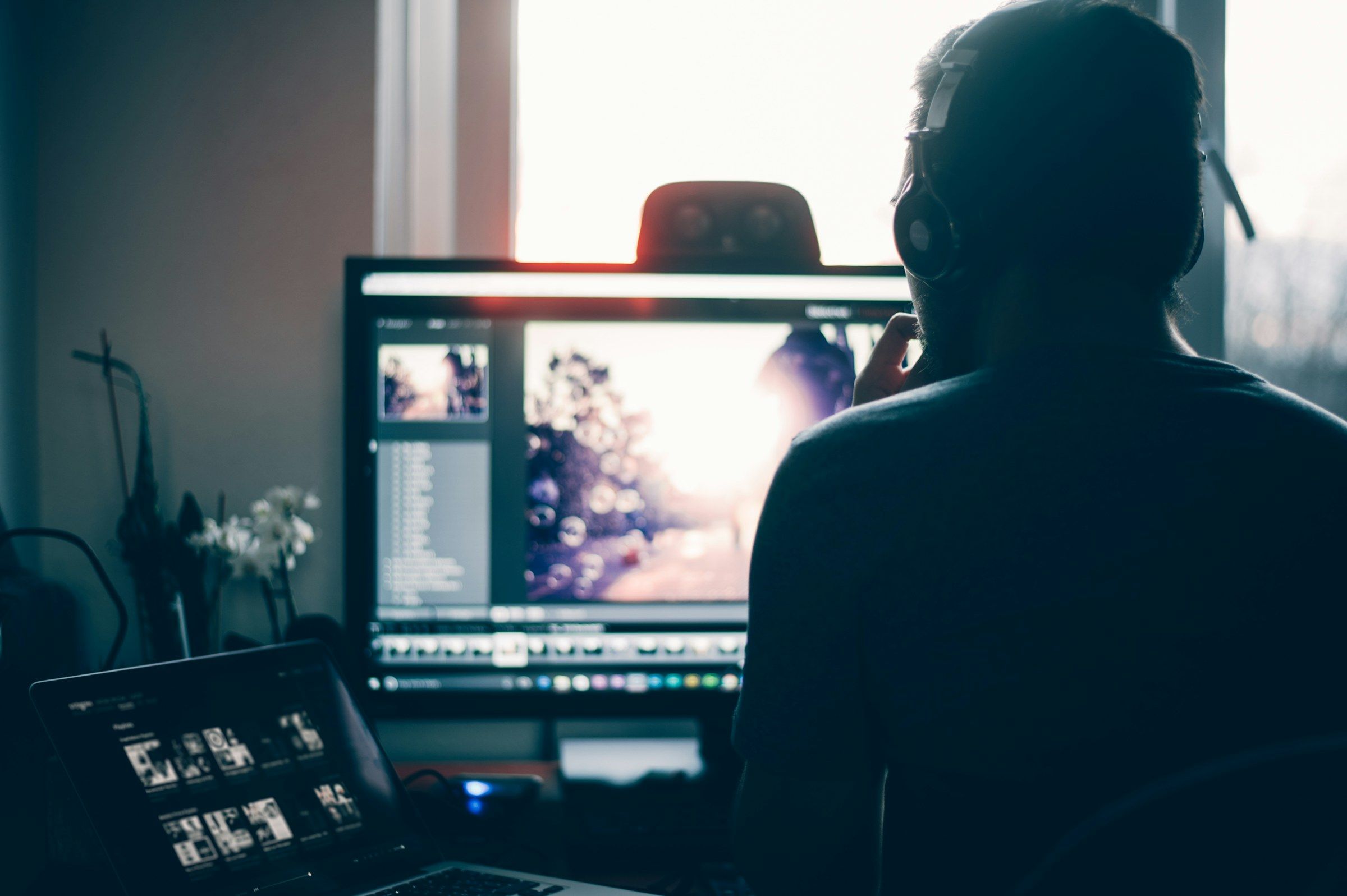 Person bearbeitet an einem großen Monitor Fotos in einem Bildbearbeitungsprogramm
