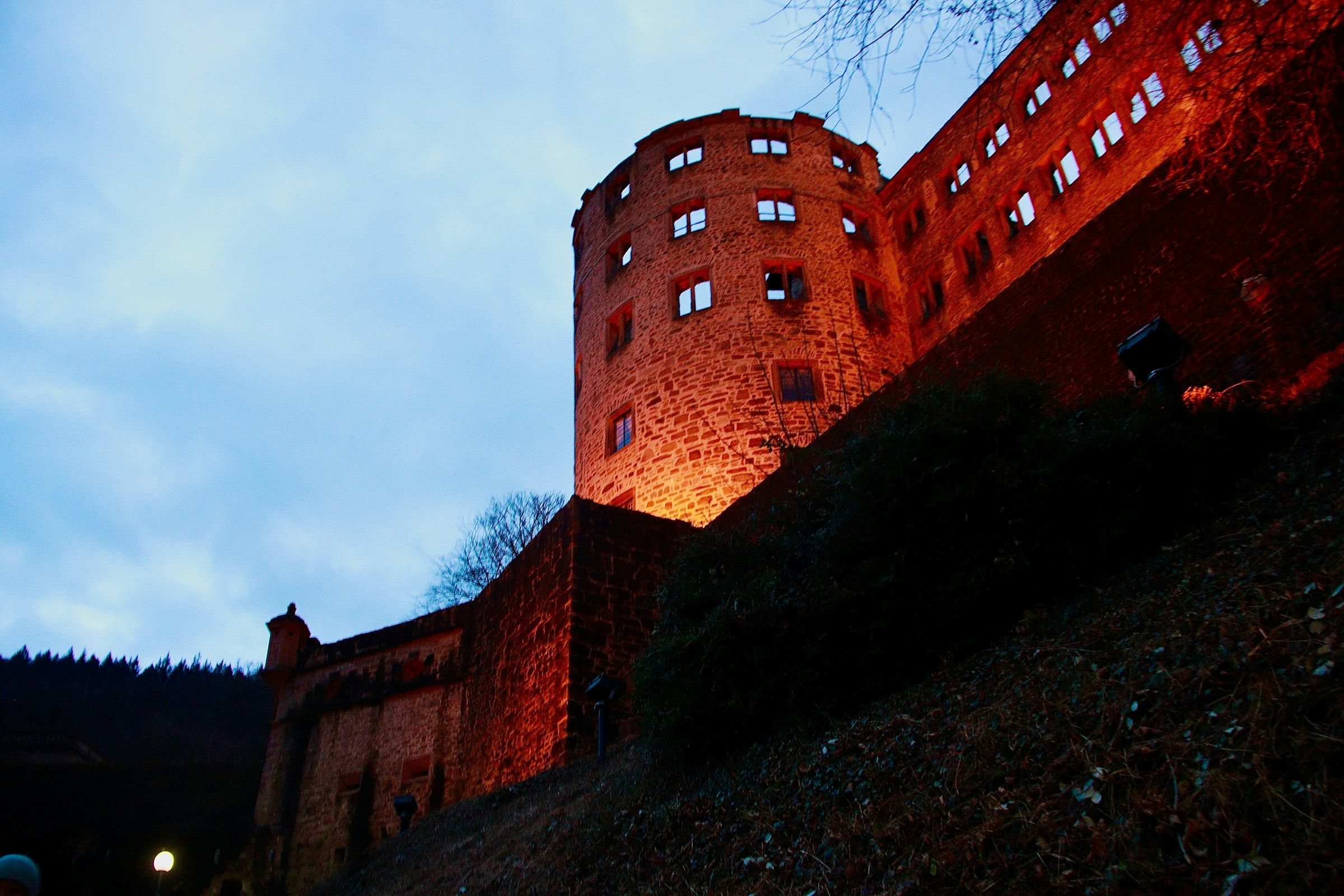 Angestrahlter roter Sandsteinturm des Heidelberger Schlosses vor blauem Abendhimmel