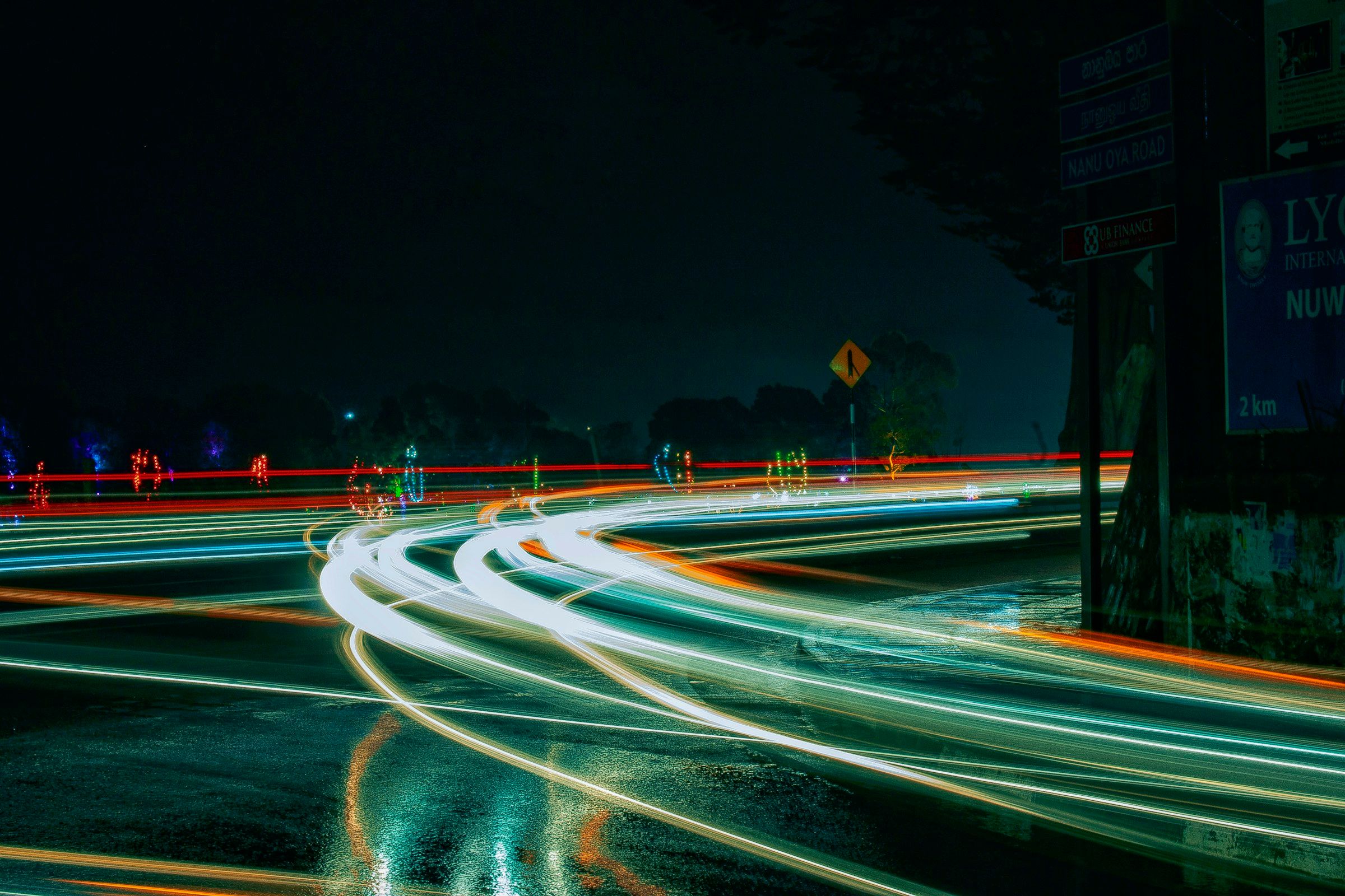 Langzeitbelichtung einer Straße bei Nacht: Autoscheinwerfer werden zu geschwungenen Lichtspuren